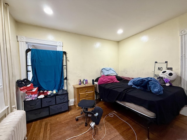 bedroom with radiator heating unit, recessed lighting, and wood finished floors