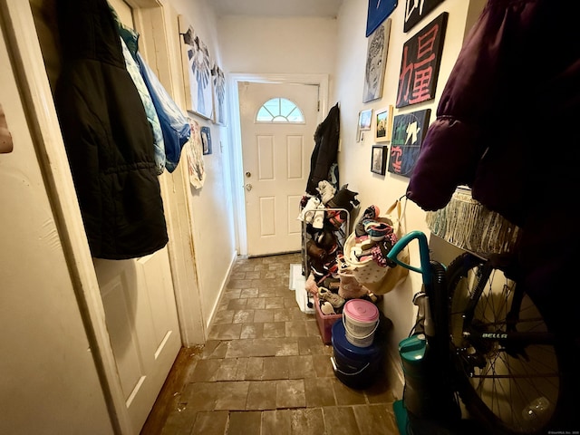 doorway to outside with stone finish floor and baseboards