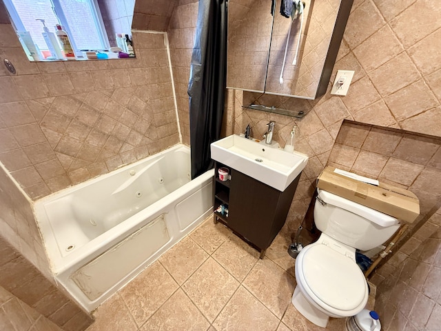 full bathroom featuring toilet, tile walls, a combined bath / shower with jetted tub, vanity, and tile patterned floors