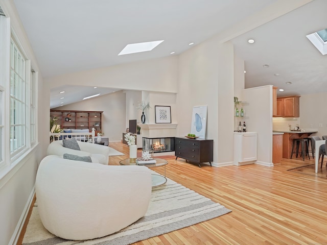 8 Argentine Way, Norwalk, CT 06850 - living room featuring a skylight, a multi sided fireplace, light wood-style flooring, vaulted ceiling, and baseboards