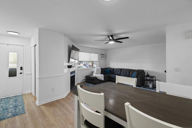 136 Pembroke Rd Unit 6-49, Danbury, CT 06811 - dining area featuring ceiling fan, a fireplace, baseboard heating, a wall mounted air conditioner, and light wood-style floors