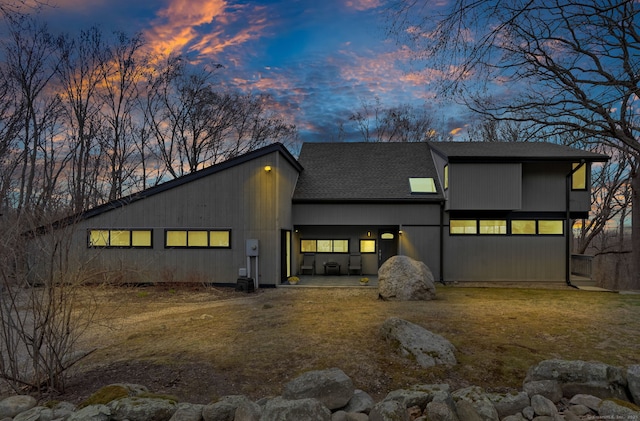 rear view of property featuring a shingled roof