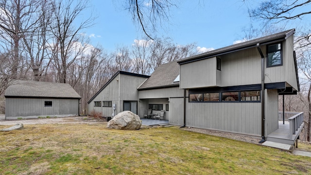 back of property featuring a lawn, a patio, and a shingled roof