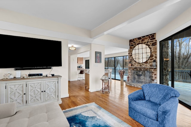 living room with baseboards, wood finished floors, beamed ceiling, and a fireplace