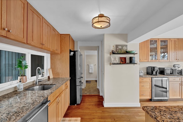 kitchen featuring wine cooler, a sink, light wood-style floors, glass insert cabinets, and light stone counters
