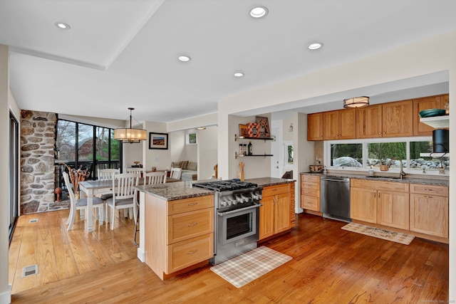 kitchen featuring stainless steel appliances, a sink, dark stone countertops, visible vents, and light wood-style floors
