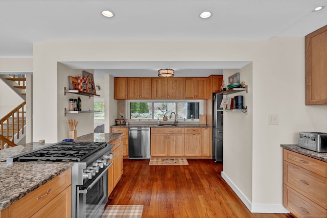 kitchen featuring open shelves, stainless steel appliances, stone countertops, and a sink