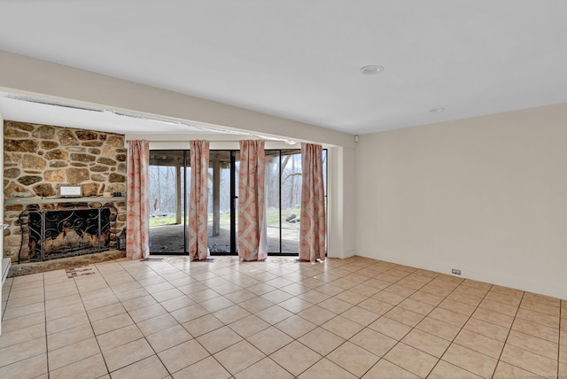 unfurnished living room with light tile patterned flooring and a stone fireplace