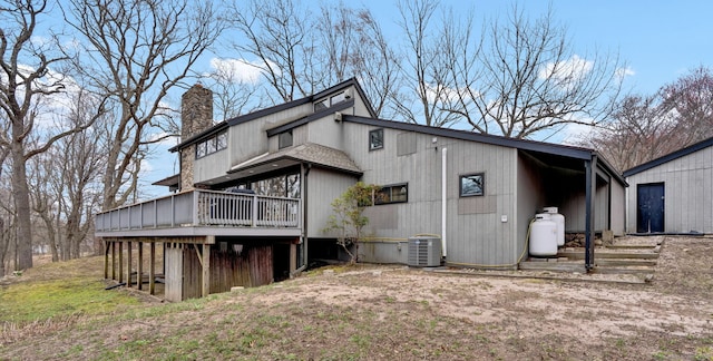 rear view of property with central AC, a wooden deck, and a chimney