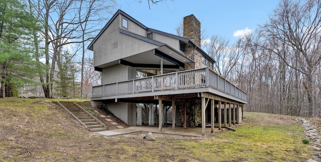 rear view of property featuring a chimney, stairway, a patio area, and a deck