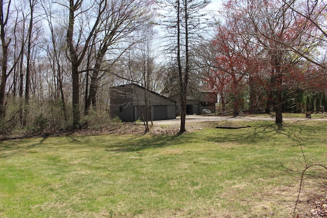 view of yard with an attached garage, driveway, and an outbuilding
