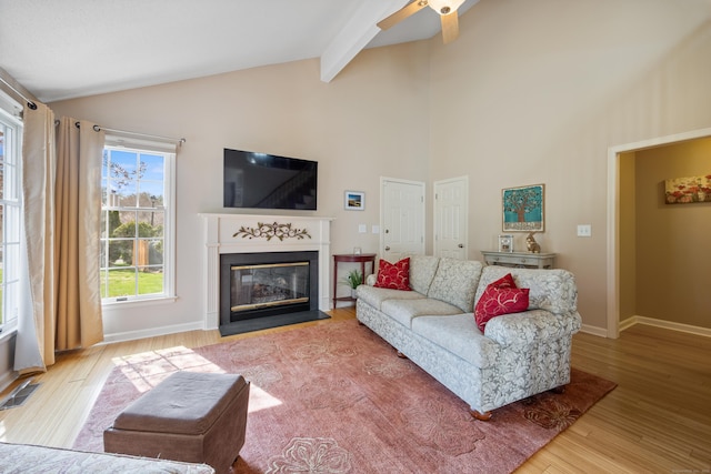 living area featuring visible vents, wood finished floors, ceiling fan, high vaulted ceiling, and a fireplace with flush hearth