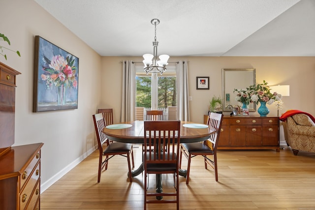 dining room featuring an inviting chandelier, baseboards, and light wood-type flooring
