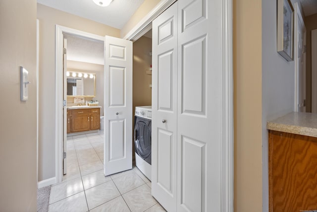 laundry area with laundry area, a sink, washer / dryer, and light tile patterned floors