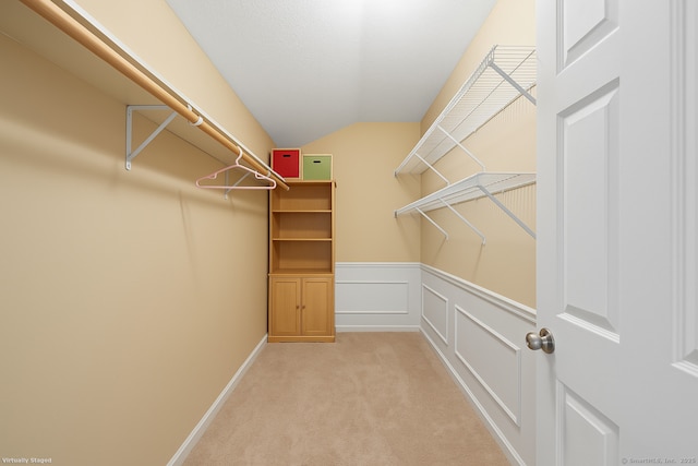 walk in closet with lofted ceiling and light colored carpet