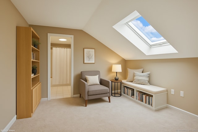 sitting room featuring vaulted ceiling with skylight, carpet floors, and baseboards