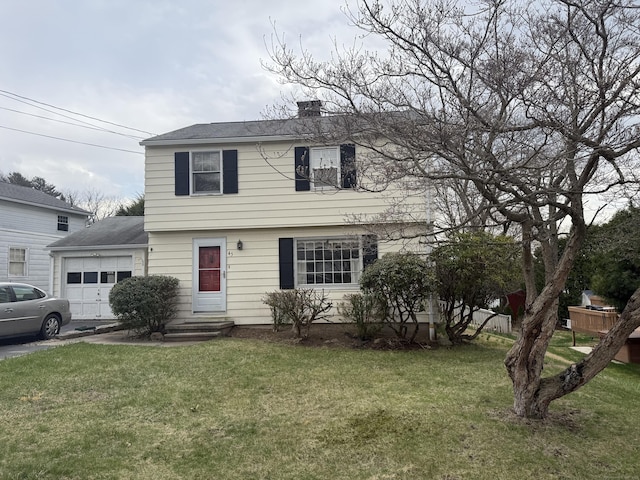 colonial-style house featuring a chimney, an attached garage, and a front yard