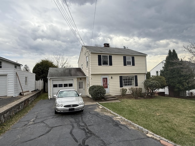 colonial house featuring a chimney, driveway, a front yard, and a garage