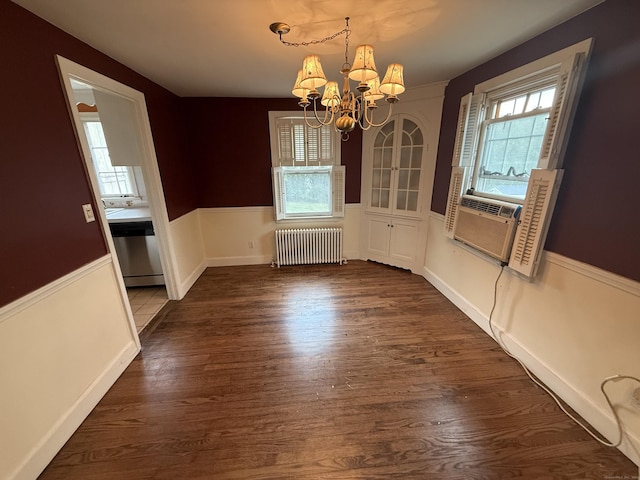 unfurnished dining area with a wainscoted wall, cooling unit, a notable chandelier, radiator heating unit, and dark wood-type flooring