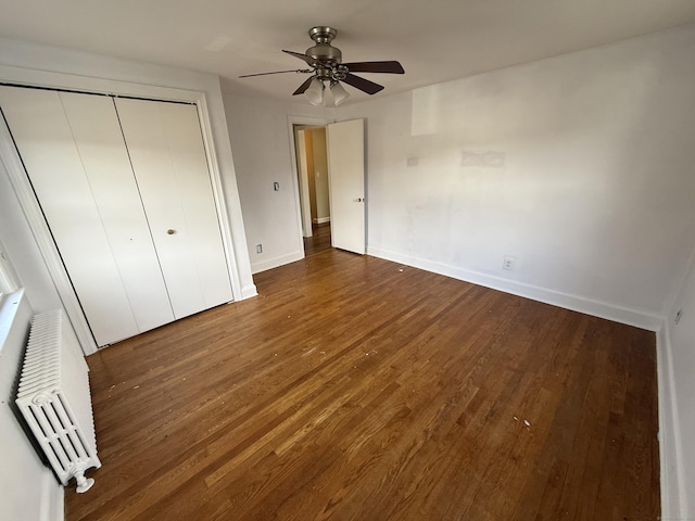 unfurnished bedroom featuring a wall mounted air conditioner, wood finished floors, a ceiling fan, a closet, and baseboards