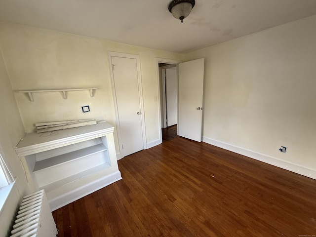 unfurnished bedroom with radiator, baseboards, and wood finished floors