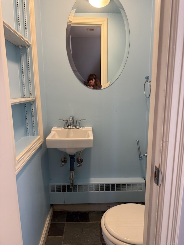 bathroom with baseboard heating, baseboards, stone finish floor, and a sink