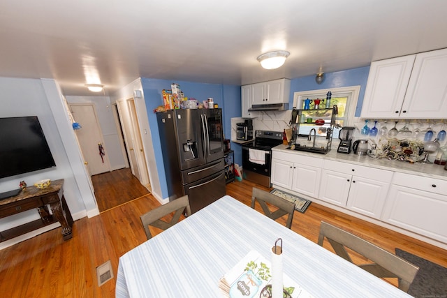 70 Manners Ave, Naugatuck, CT 06770 - kitchen with stainless steel refrigerator with ice dispenser, range with electric stovetop, under cabinet range hood, decorative backsplash, and wood finished floors
