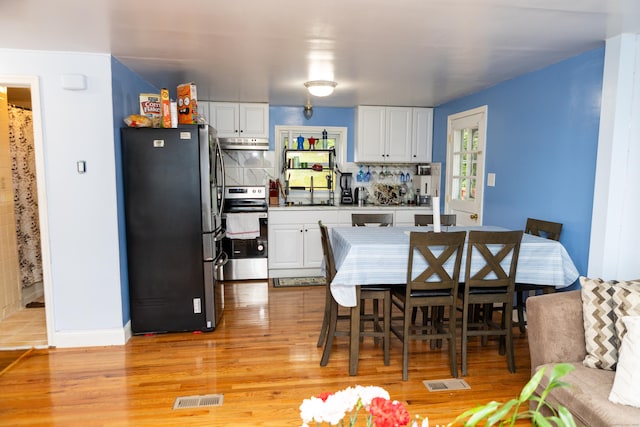 70 Manners Ave, Naugatuck, CT 06770 - kitchen with appliances with stainless steel finishes, under cabinet range hood, white cabinets, and light wood-type flooring
