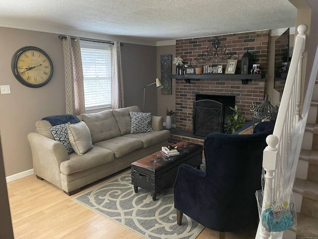 living room featuring a brick fireplace, a textured ceiling, baseboards, and wood finished floors