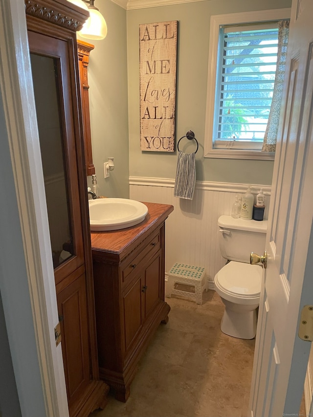 half bathroom with toilet, a wainscoted wall, and vanity