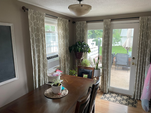 dining space featuring cooling unit, a textured ceiling, and light wood-type flooring