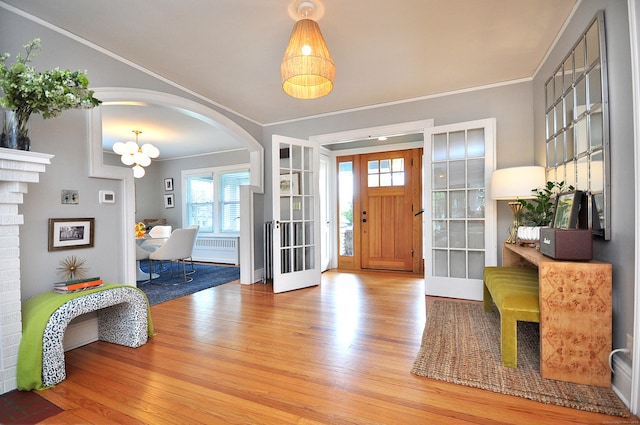 1186 Farmington Ave, West Hartford, CT 06107 - foyer with radiator heating unit, wood finished floors, crown molding, arched walkways, and a chandelier