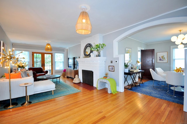 1186 Farmington Ave, West Hartford, CT 06107 - living room featuring arched walkways, wood-type flooring, a chandelier, a brick fireplace, and crown molding