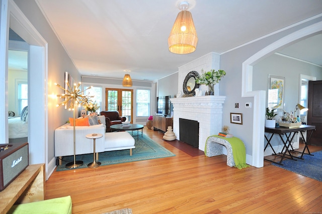 1186 Farmington Ave, West Hartford, CT 06107 - living room featuring wood finished floors, arched walkways, a brick fireplace, crown molding, and baseboards