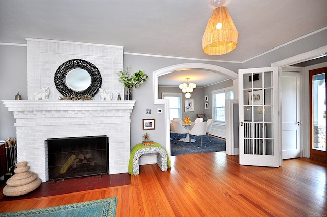 1186 Farmington Ave, West Hartford, CT 06107 - living area featuring wood finished floors, arched walkways, crown molding, and a brick fireplace