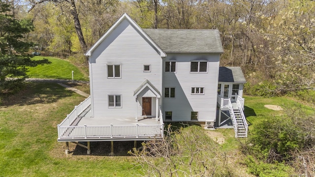rear view of house featuring roof with shingles, a yard, and a deck