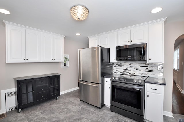 27 Brook St, New Britain, CT 06051 - kitchen with stainless steel appliances, dark countertops, white cabinets, decorative backsplash, and arched walkways