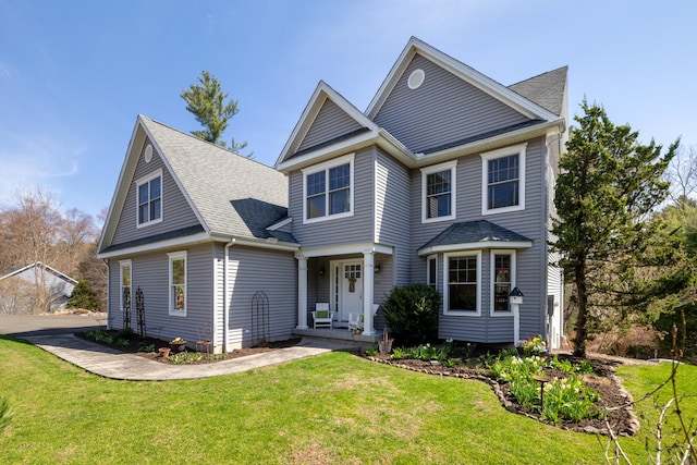 view of front facade with a front lawn, a porch, and a shingled roof
