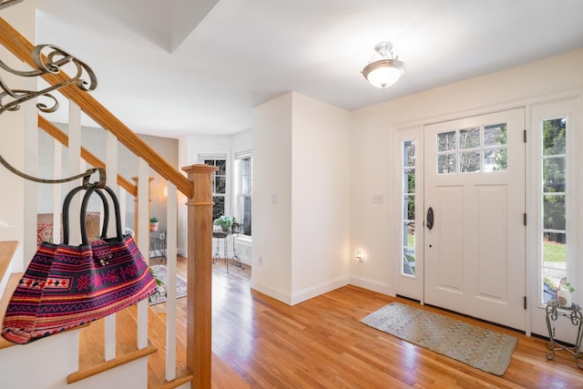 entryway featuring stairway, baseboards, light wood-type flooring, and plenty of natural light