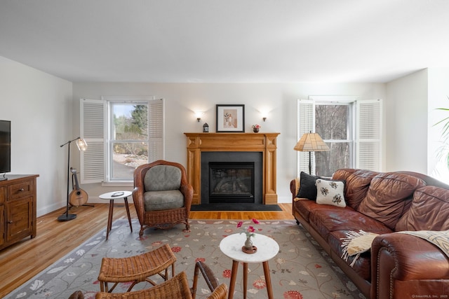 living room with a fireplace with flush hearth, baseboards, and wood finished floors