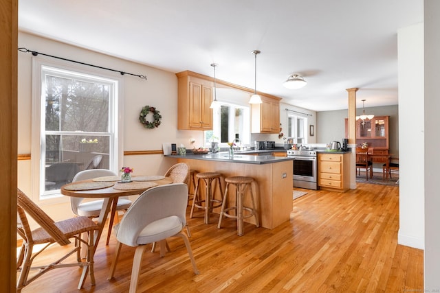 kitchen with stainless steel electric stove, light brown cabinetry, pendant lighting, light wood finished floors, and a peninsula