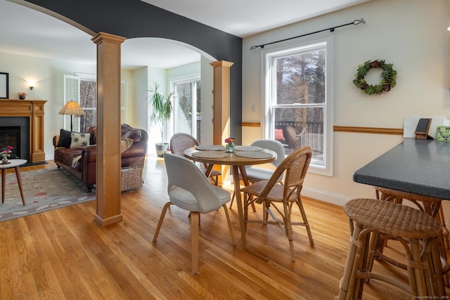 dining room featuring arched walkways, light wood-type flooring, and ornate columns
