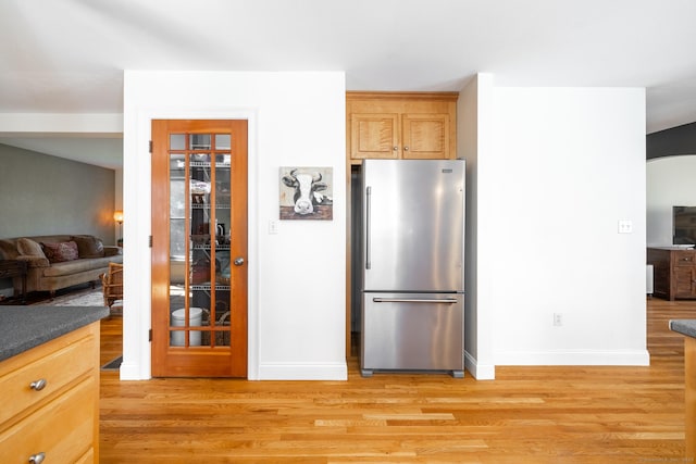 kitchen featuring freestanding refrigerator, dark countertops, light wood finished floors, and baseboards