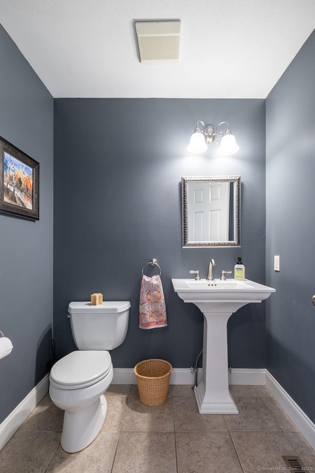 bathroom with toilet, tile patterned floors, visible vents, and a sink