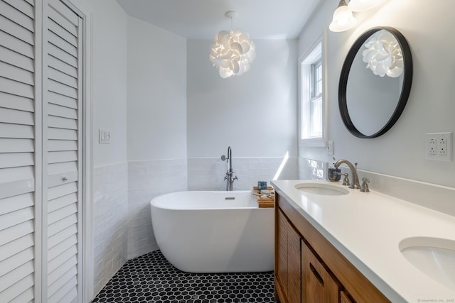 full bathroom with tile patterned floors, double vanity, a sink, tile walls, and a soaking tub