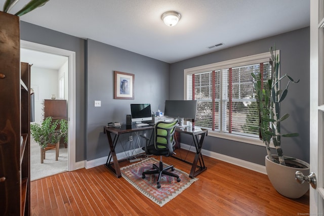 office area with visible vents, wood finished floors, and baseboards