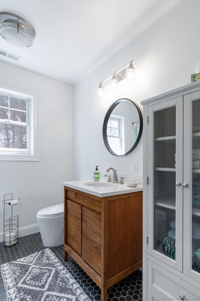 bathroom with toilet, vanity, and visible vents