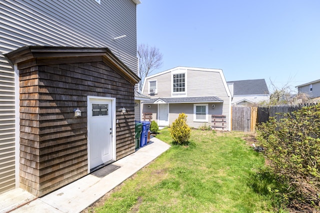 rear view of property featuring fence, a lawn, and an outbuilding