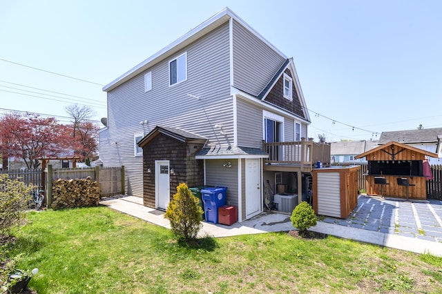 rear view of house featuring fence, a wooden deck, outdoor dry bar, cooling unit, and a lawn
