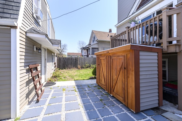 view of patio / terrace with fence, an outdoor structure, and a shed